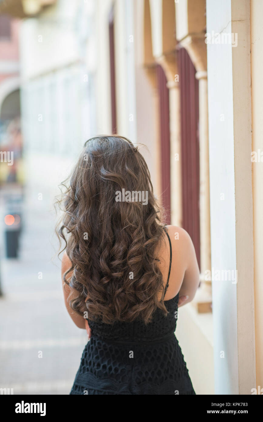 Rear view of a young woman with wavy hair standing outdoors Stock Photo ...