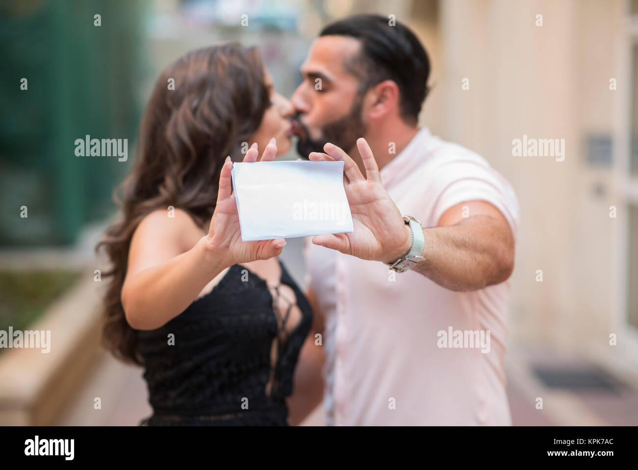 Man and woman kissing while holding a blank card Stock Photo