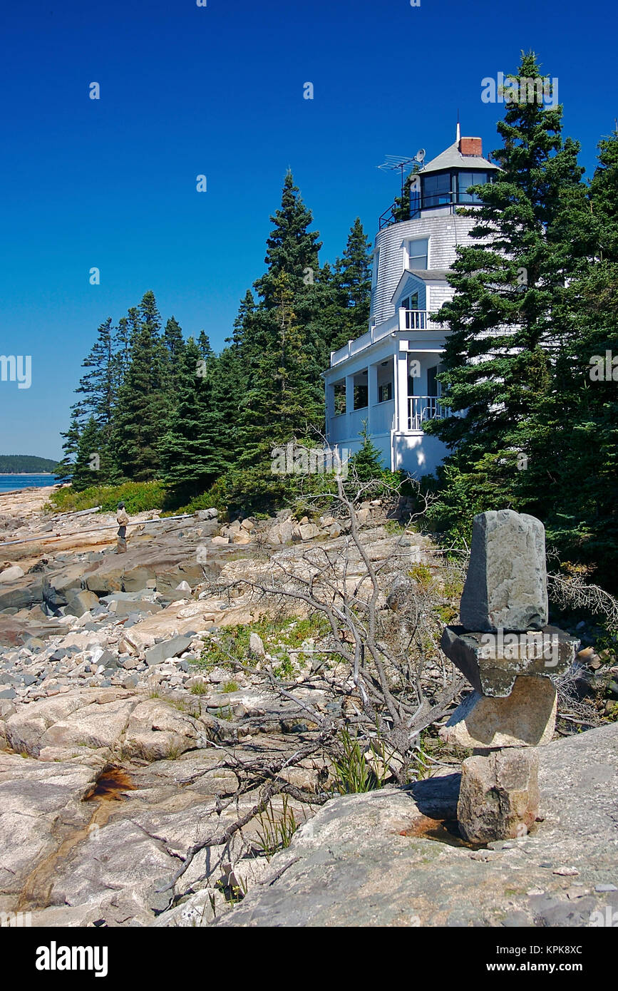 USA, Maine, Schoodic Peninsula. A home with a lighthouse-like tower above the rocks overlooking the ocean, stacked stones in the foreground Stock Photo