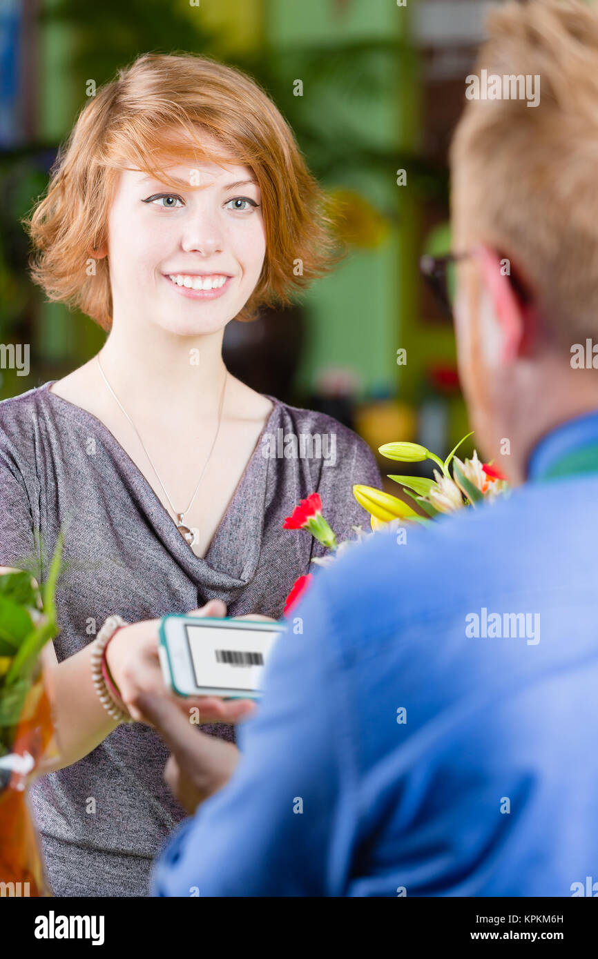 Smiling Young Flower Shop Customer using Electronic Coupon Stock Photo