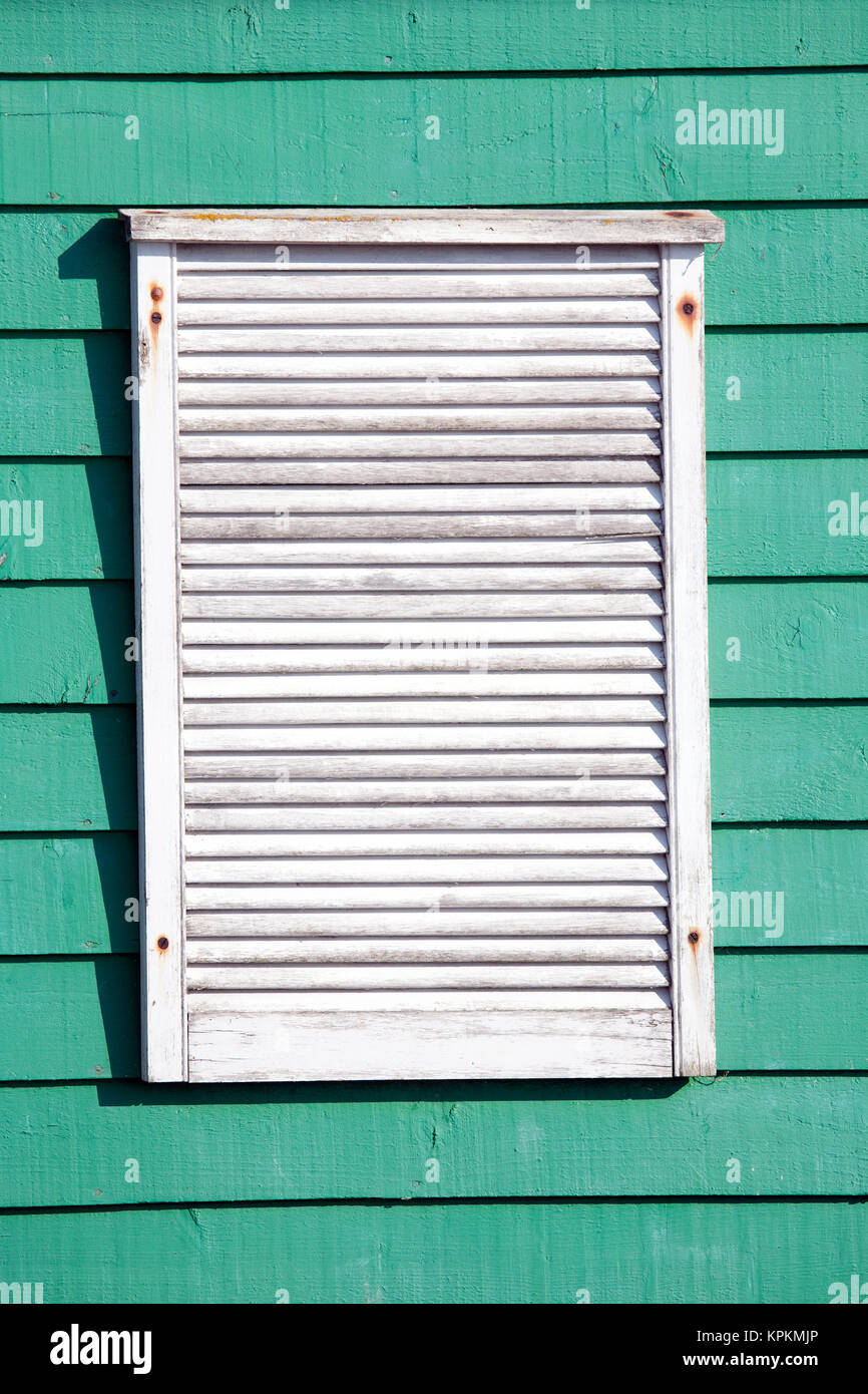 White louvred wooden vent on turquoise or green weather boarded building Stock Photo