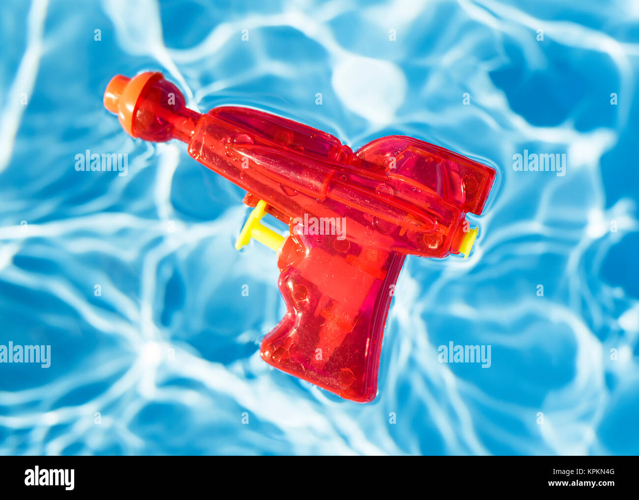 Red squirt gun floating in a pool. Stock Photo