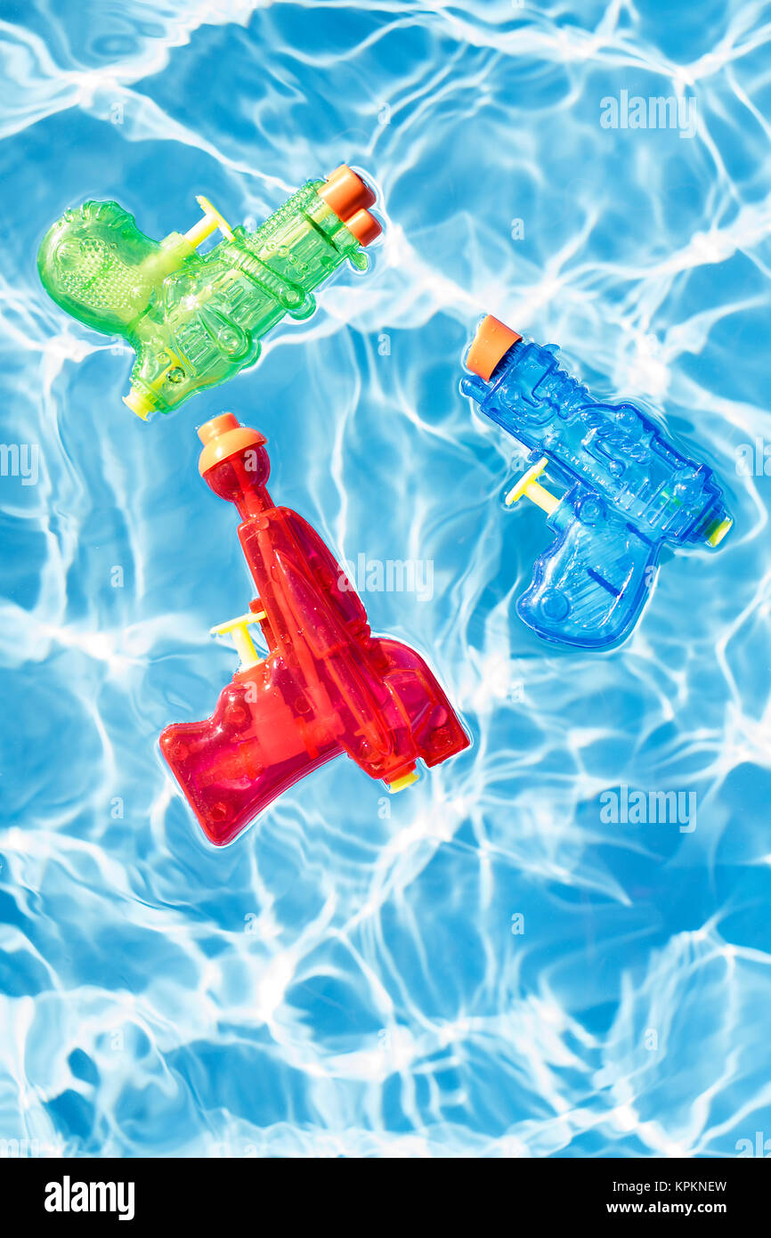 Three colorful squirt guns floating in water. Stock Photo