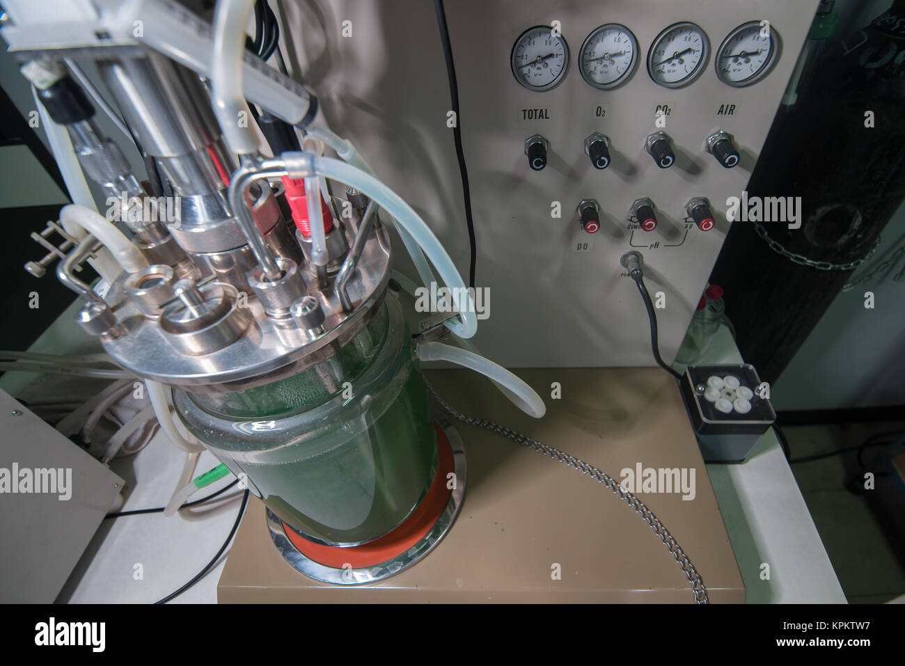 Close up of large glass beaker with green fluid, tubing and metallic parts for lab Stock Photo