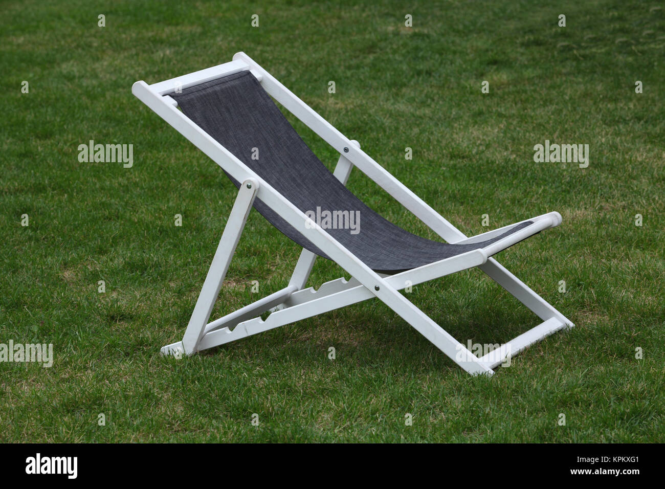 White wooden deck chair on green grass Stock Photo - Alamy
