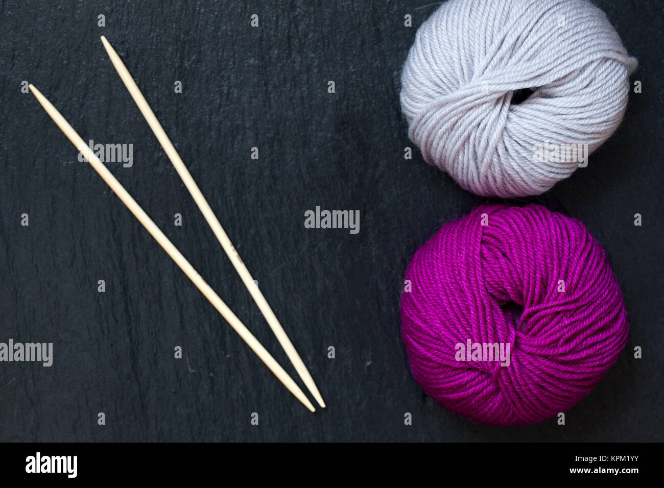 wool ball inf pink and gray on black slate plate with bamboo knitting needles Stock Photo