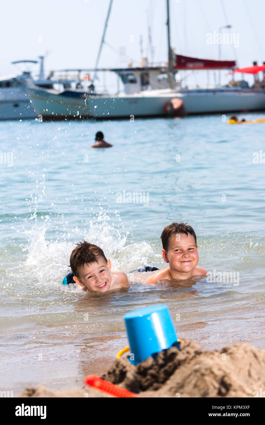 young boys lying in the sea and splashing water Stock Photo - Alamy
