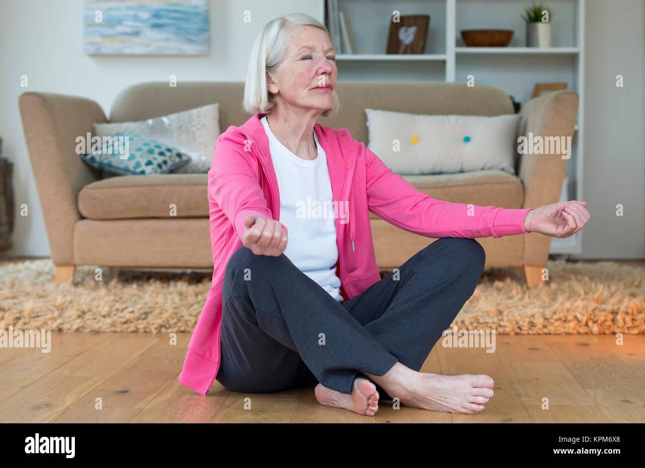Elderly lady meditating at home Stock Photo