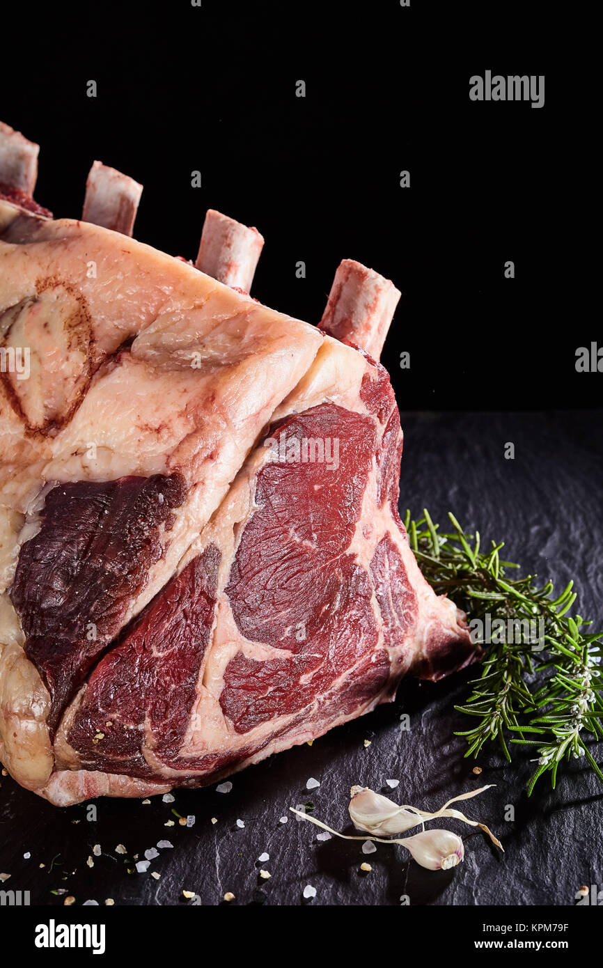 Close up on piece of uncooked cote de boeuf beef ribs with garlic and