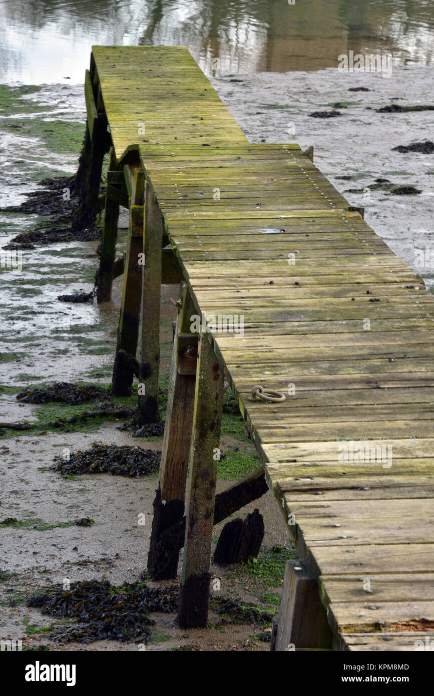 a rickety old wooden boardwalk or plank jetty on the river medina, isle