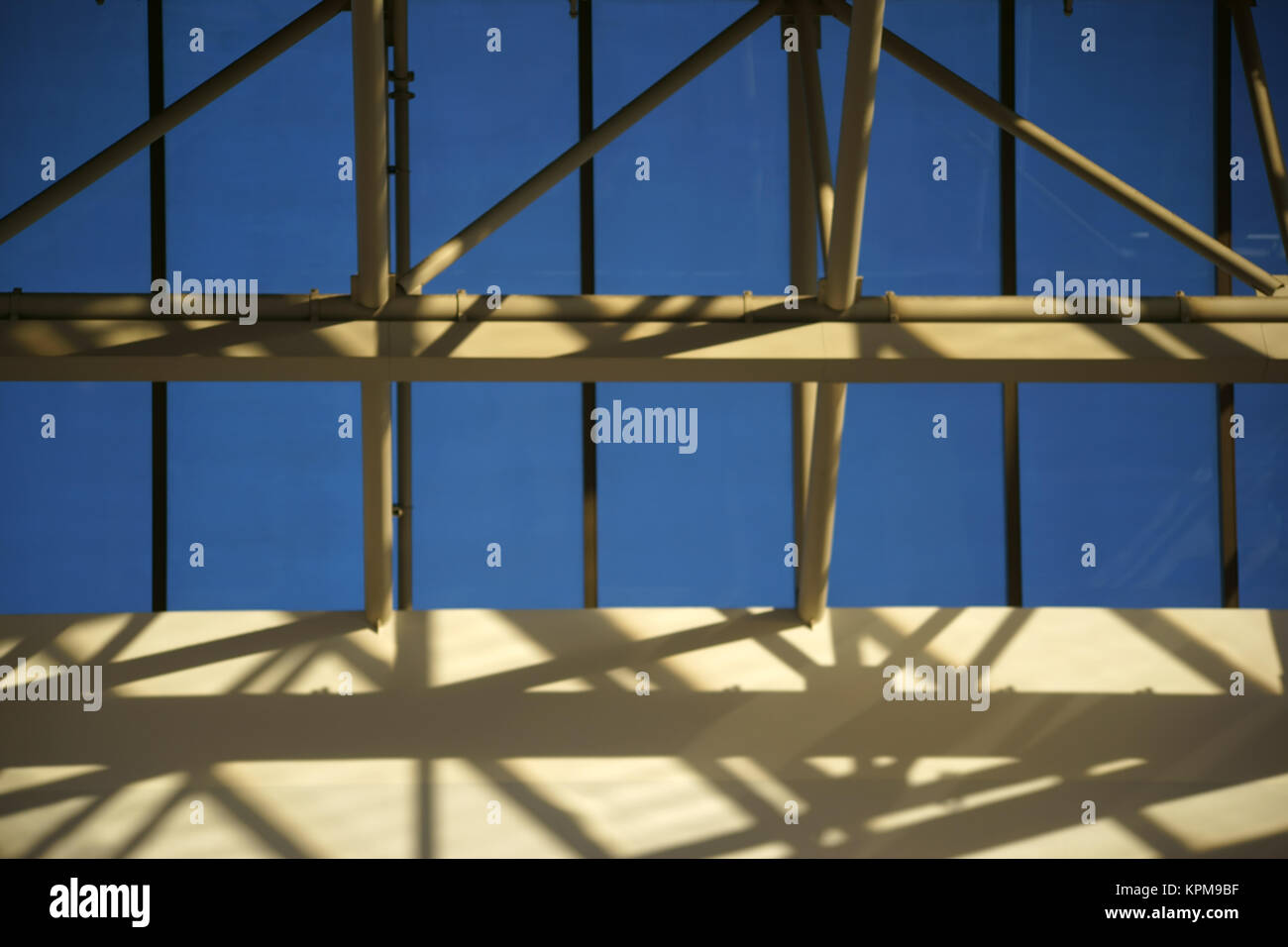 Eine Dachkonstruktion aus einem Stahlpfeilern und Querstreben wirft Schatten an die Wand. Stock Photo