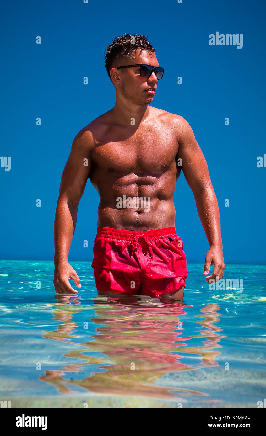 Handsome muscular man wearing sunglasses in sea water Stock Photo