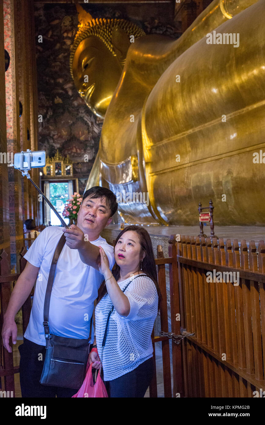 Bangkok, Thailand.  Reclining Buddha, Wat Pho Temple Complex, Asian Couple Doing a Selfie. Stock Photo