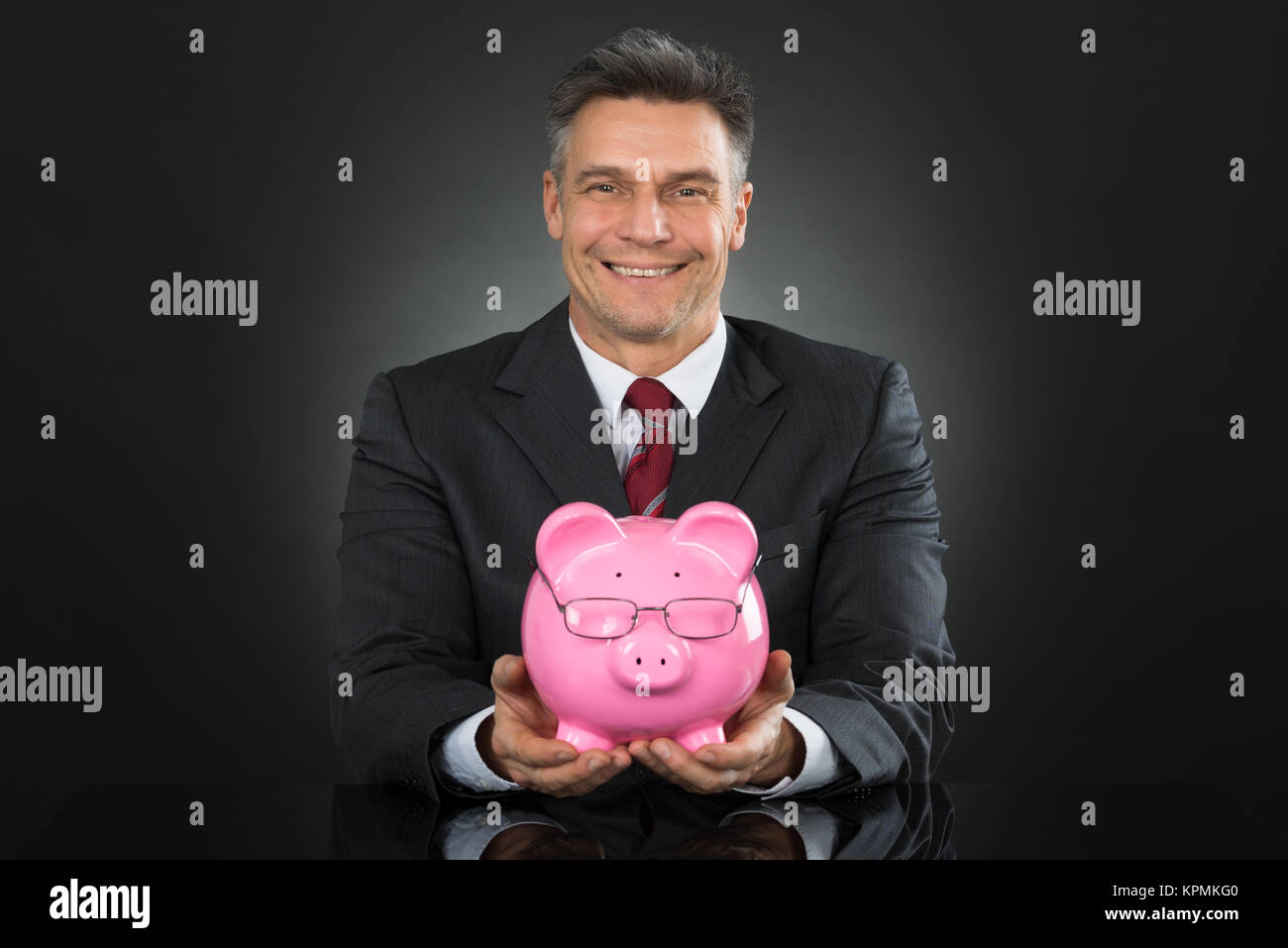 Businessman Sitting And Holding Piggybank Stock Photo