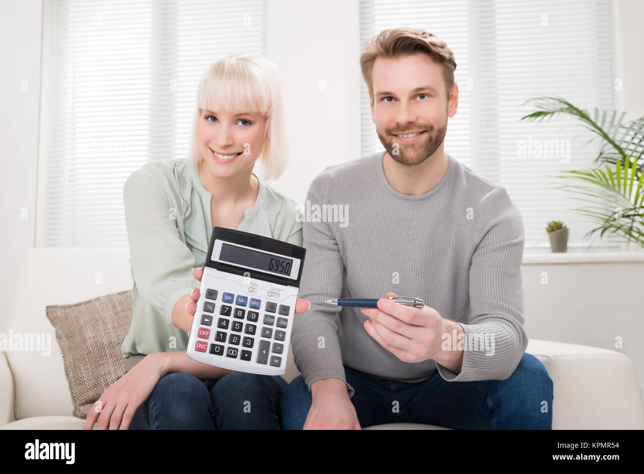 Happy Couple Showing Calculator Stock Photo Alamy