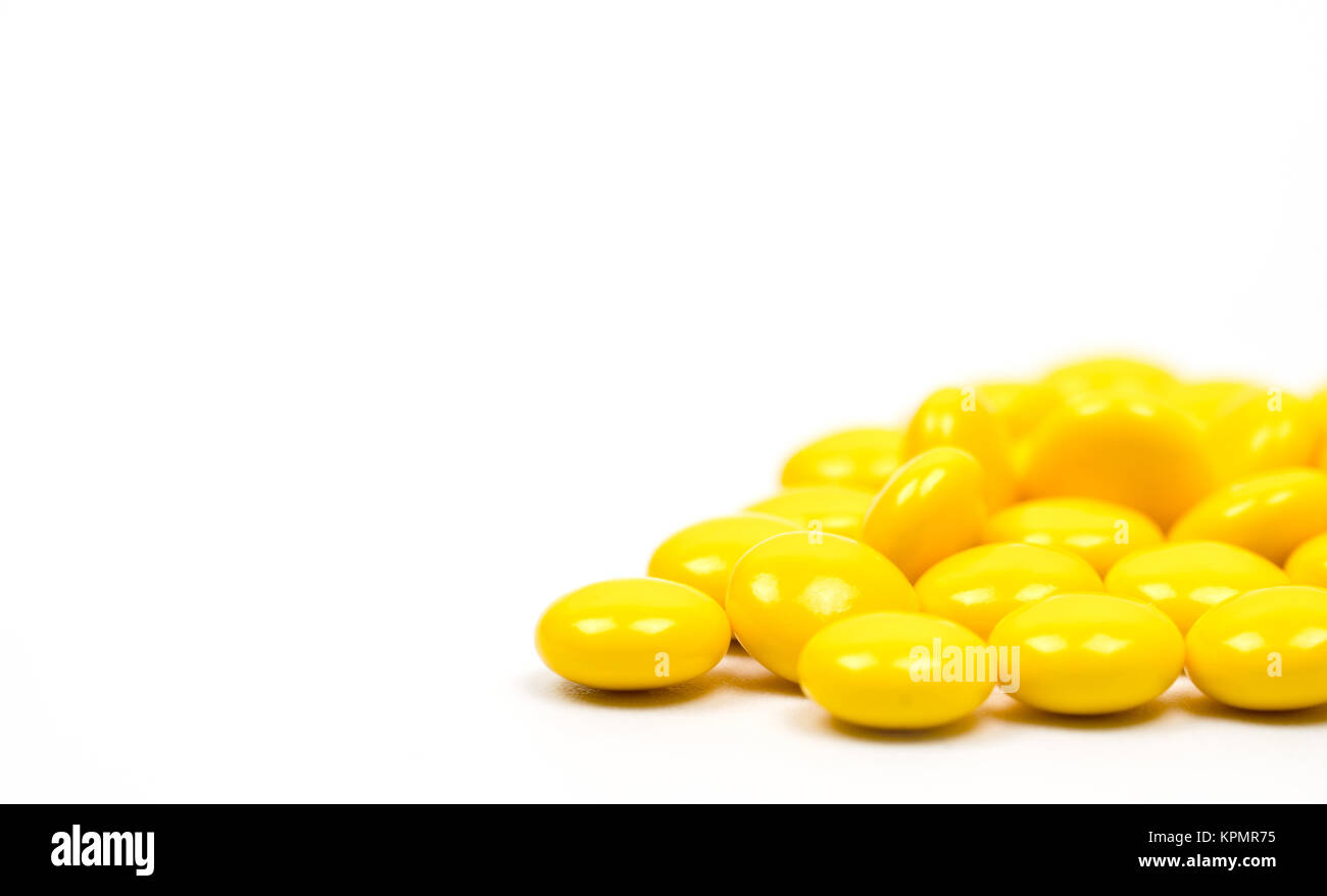 Yellow sugar coated tablets pills on white background with copy space. Medicine for treatment