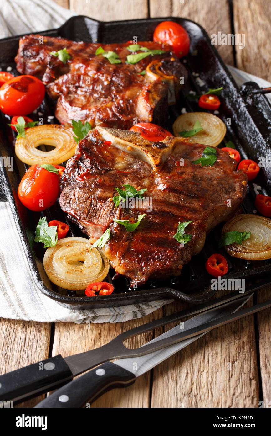Tasty barbecue T Bone steak with tomato, chili and onions on the grill