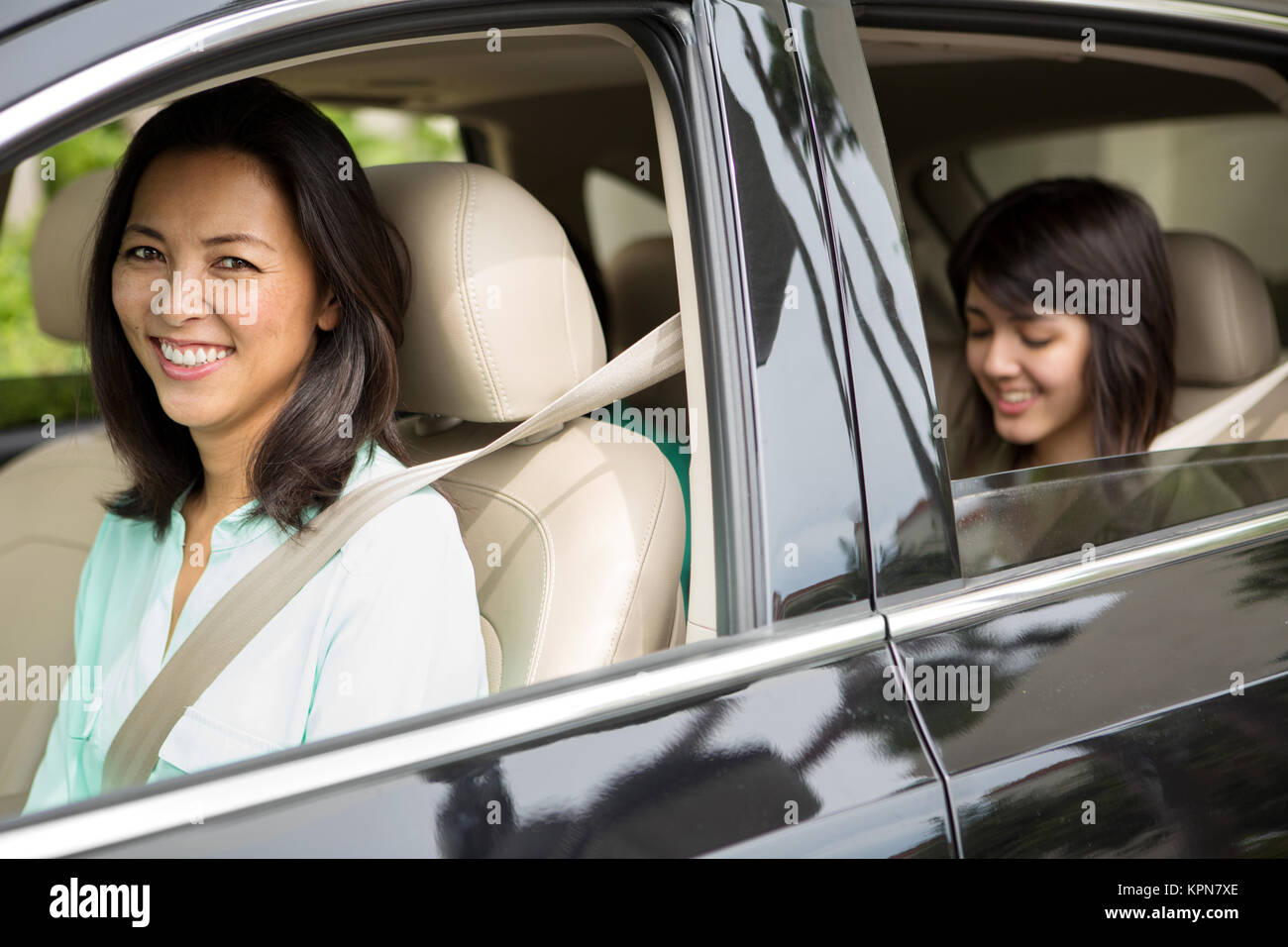 Happy Asian mother driving her teen daughter. Stock Photo