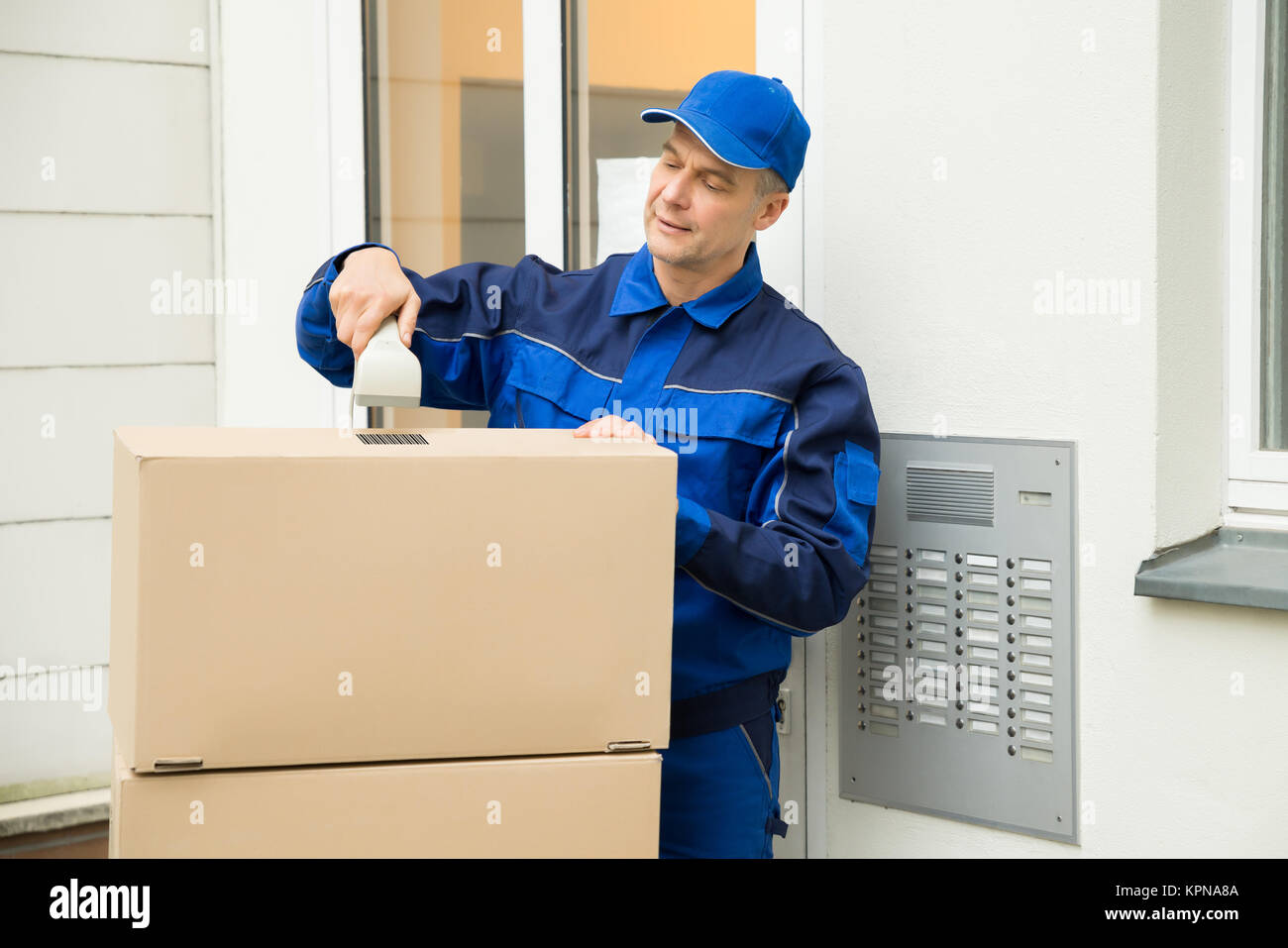Delivery Man Scanning Cardboard Boxes With Barcode Scanner Stock Photo