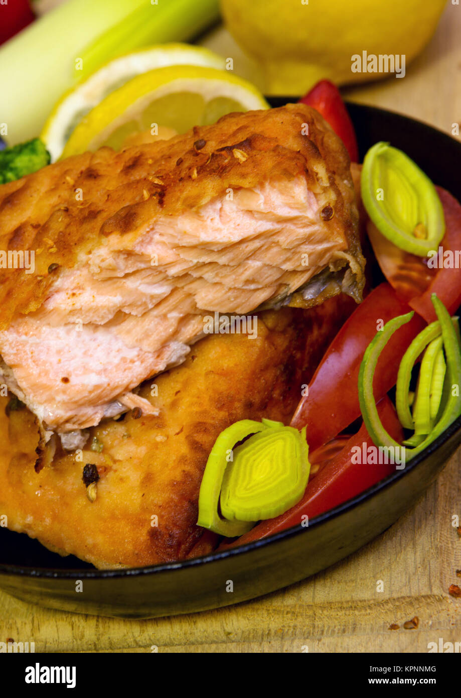 Frying pan with salmon fillets and vegetables . studio shot Stock Photo