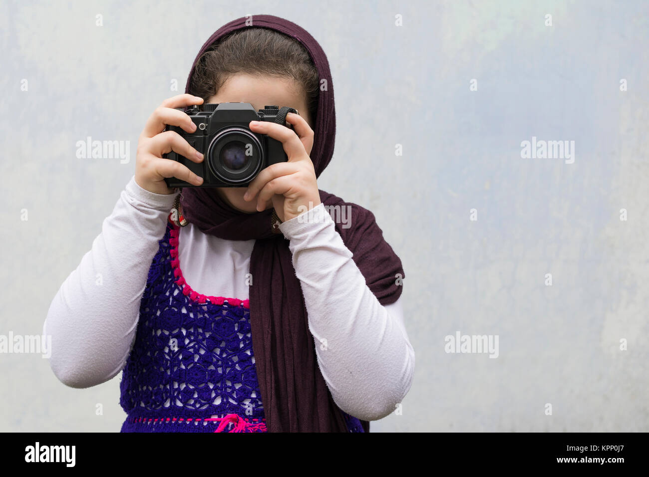 Young Little Girl Is Taking Photograph by An old Analogue Camera Strapped on Her Neck. Stock Photo