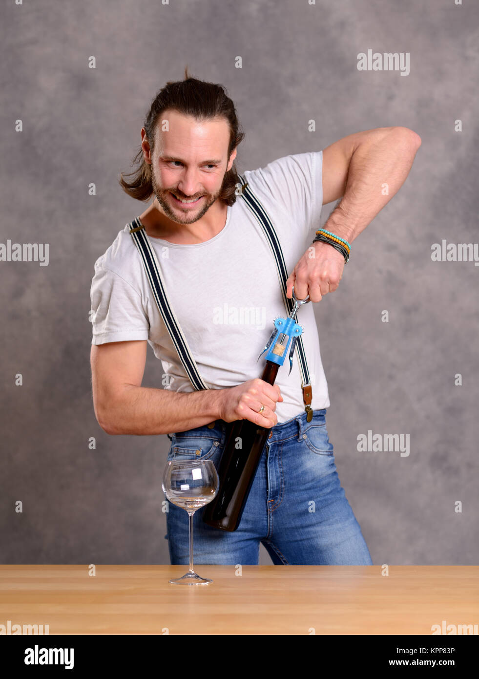 young man standing at the table and opening red wine Stock Photo - Alamy