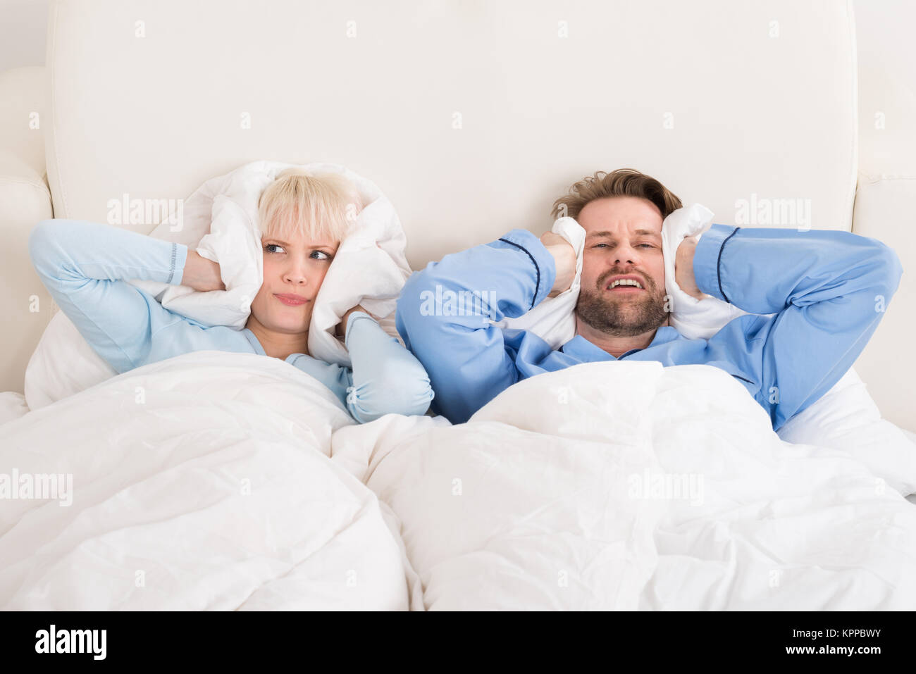 Couple Covering Ears While Sleeping On Bed Stock Photo Alamy