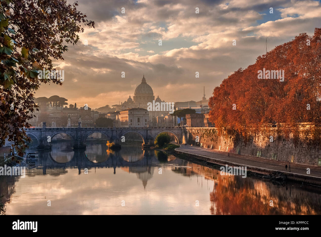 Autumn leaves along River Tiber in Rome with Saint Peter dome and Holy Angel Bridge at sunset Stock Photo