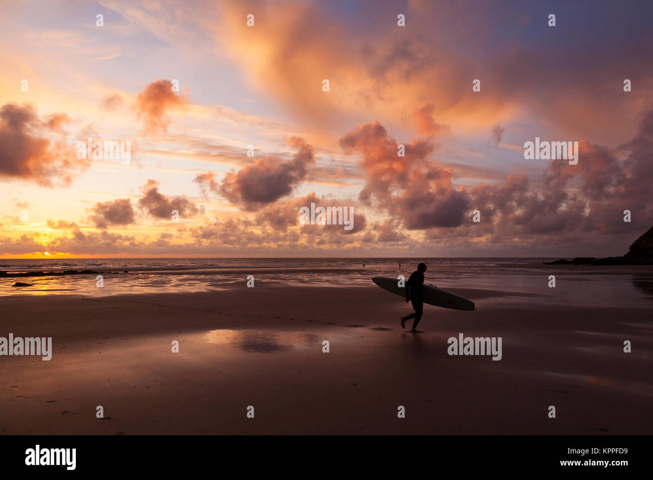 Sunset on Porthtowan beach in Cornwall with silhouetted surfer. Stock Photo
