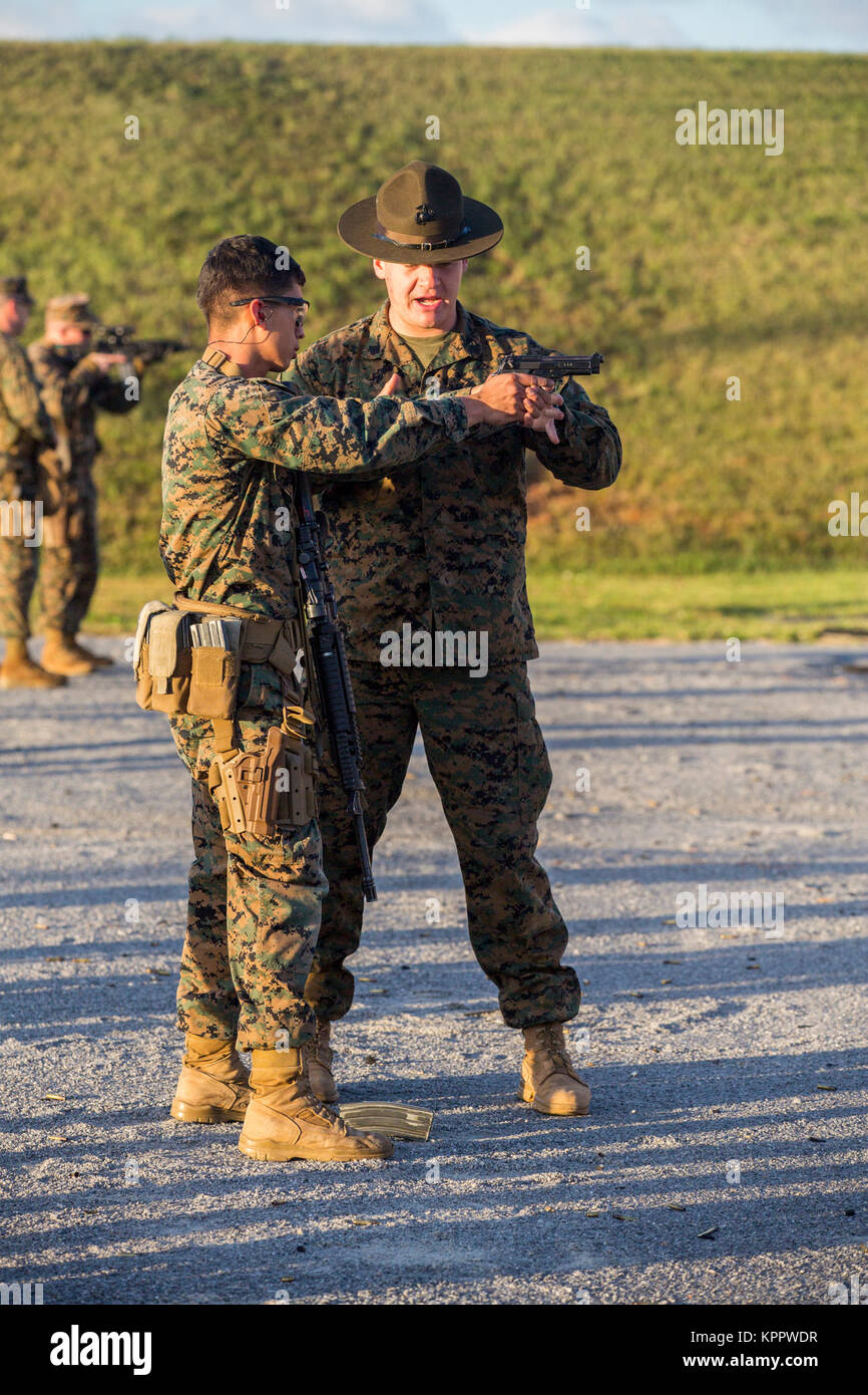 U.S. Marine Corps Sgt. Dylan N. Catham, an instructor with Weapons Training Battalion, Headquarters Marine Corps, assists a Marine with his grip during the Far East Annual Marksmanship Competition on Camp Hansen, Okinawa, Japan, on Dec. 6, 2017. The purpose of the competition is to improve the marksmanship, proficiency, and combat readiness of the Marine Corps as well as provide an opportunity to win a reward and advance to the Marine Corps Championship in Quantico, Virginia. Catham is a native of Plainfield, Ill. (U.S. Marine Corps Stock Photo