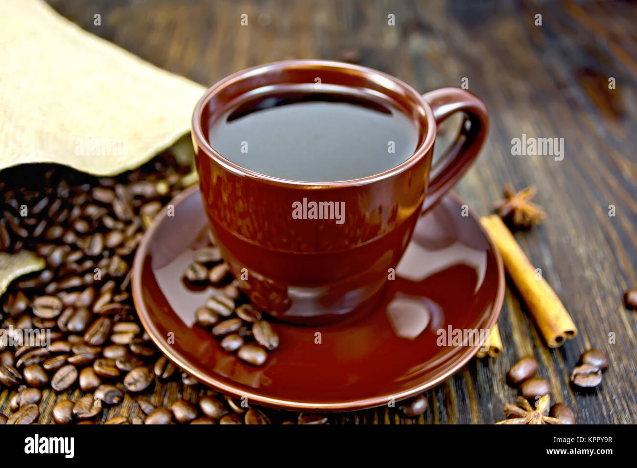 Coffee in brown cup with cinnamon and bag on board Stock Photo