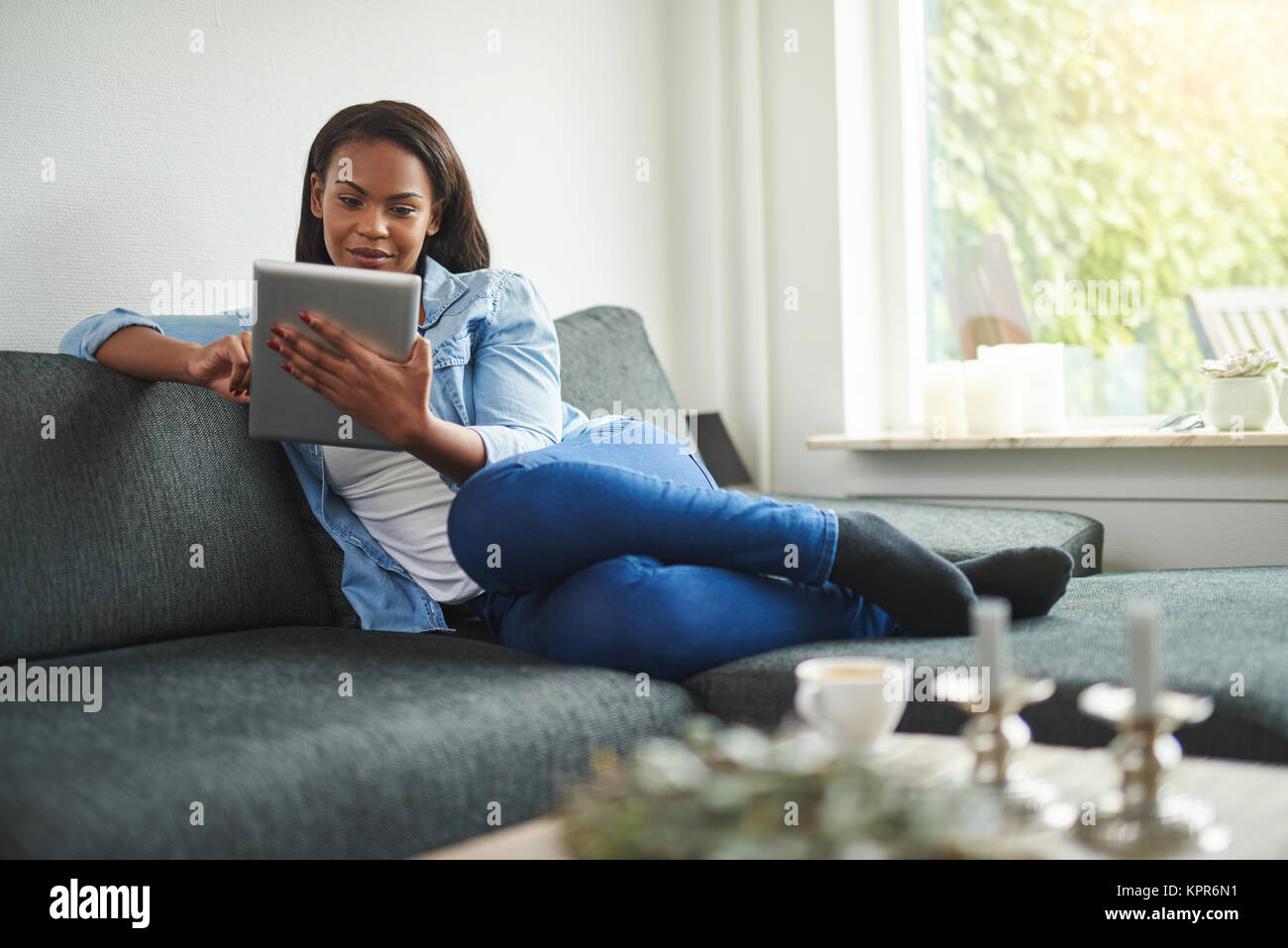 Young African woman relaxing the sofa in her living room at home ...