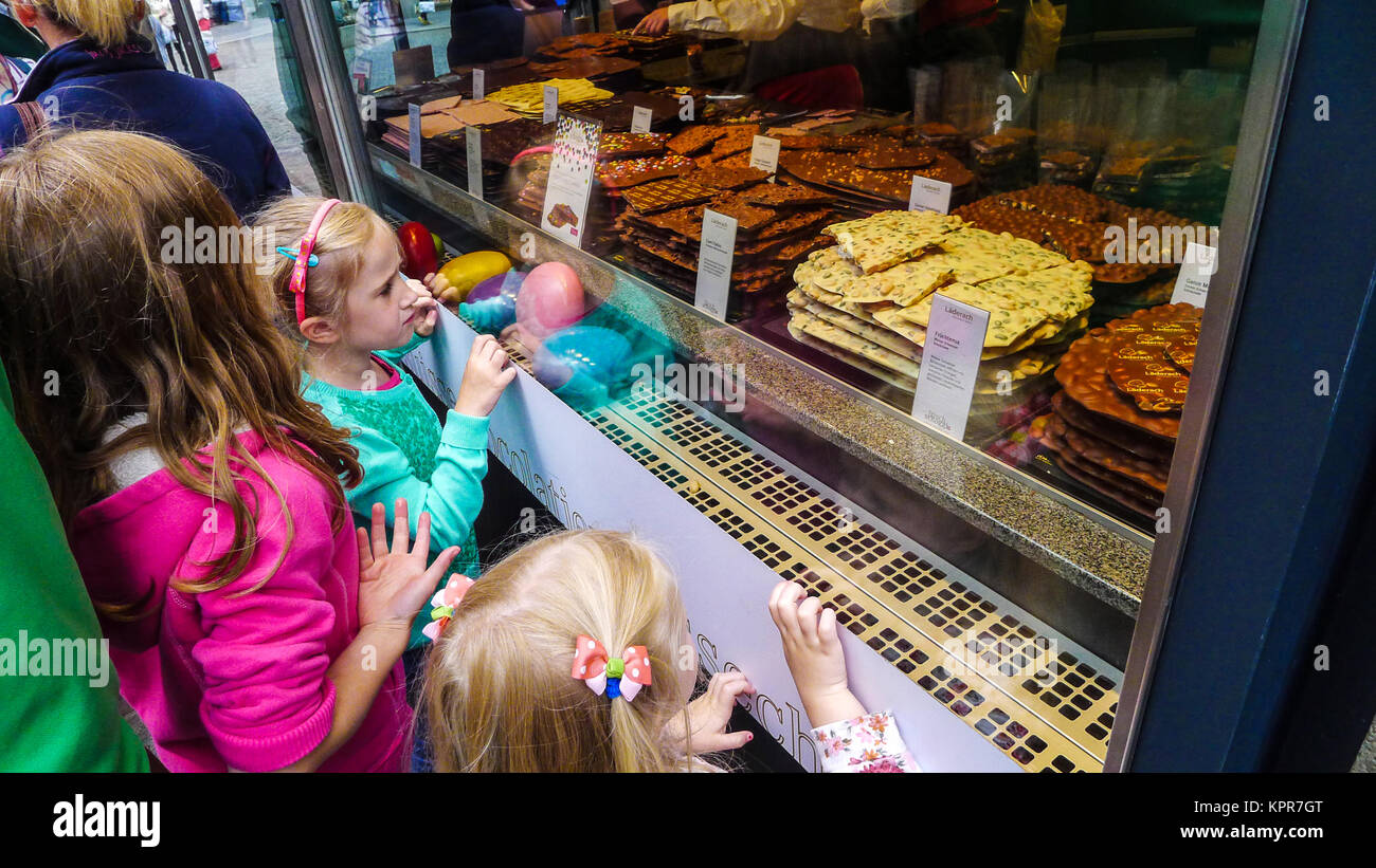 Children looking into a shop window with cookies on display in the window, looking longingly and hungry Stock Photo