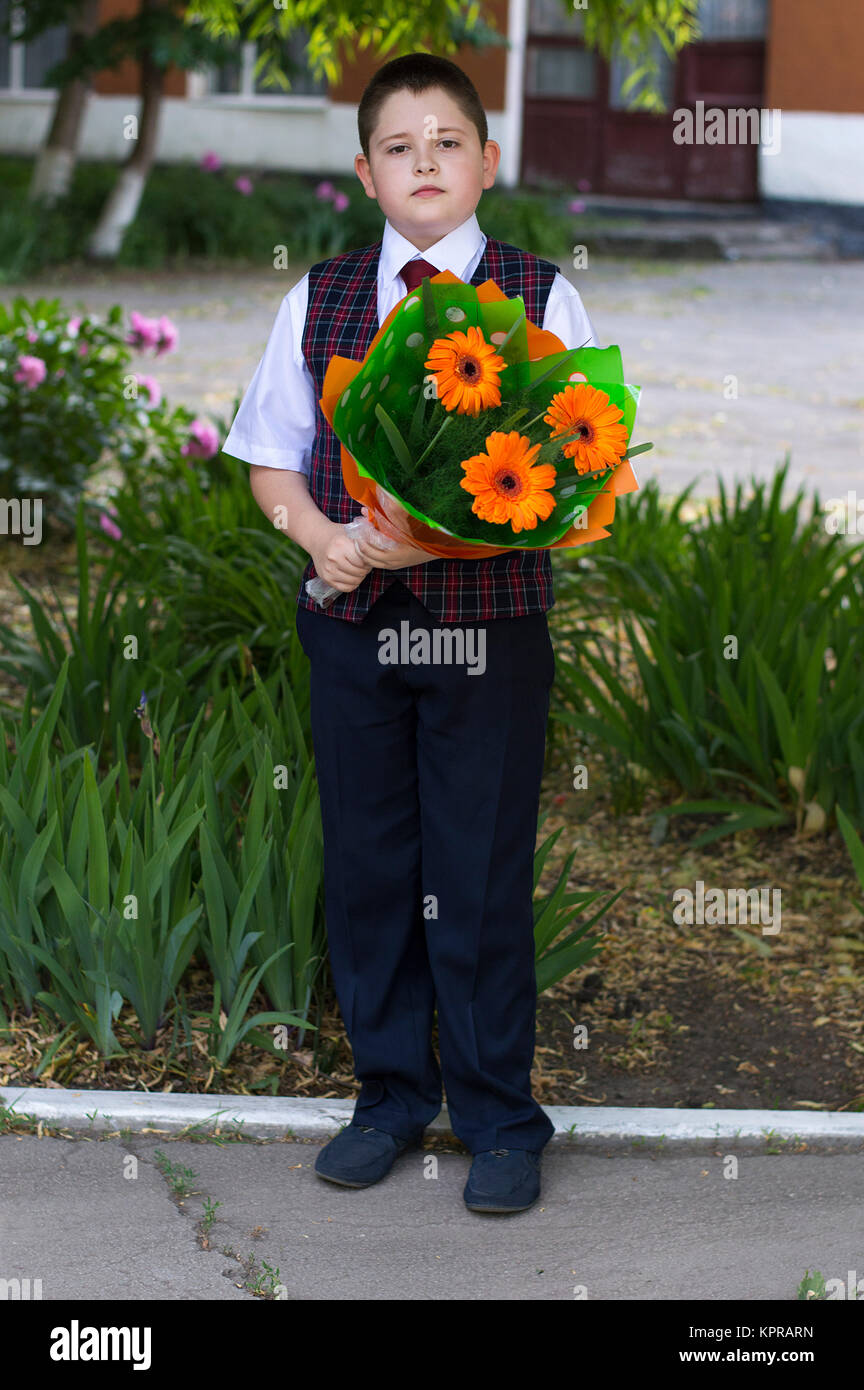 the lovely school student costs with a bouquet of flowers Stock Photo