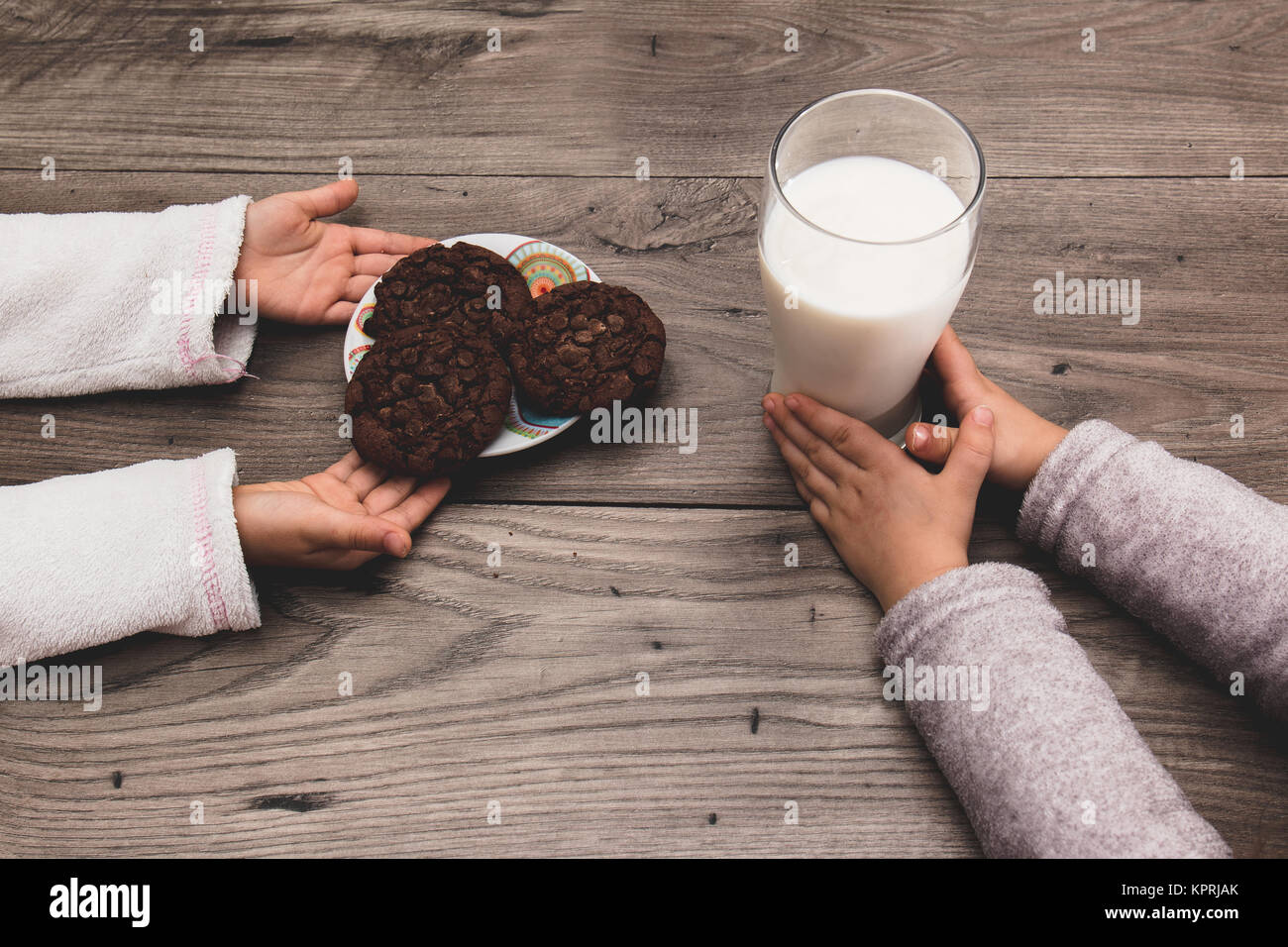 Close up of two children leaving cookies and milk on the table for