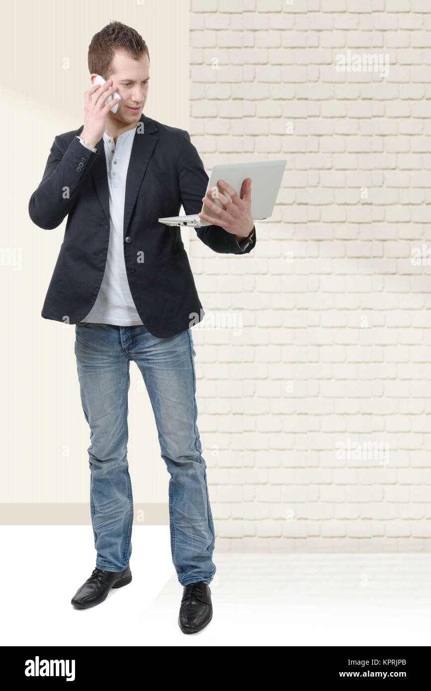 young man standing with laptop and phone Stock Photo - Alamy