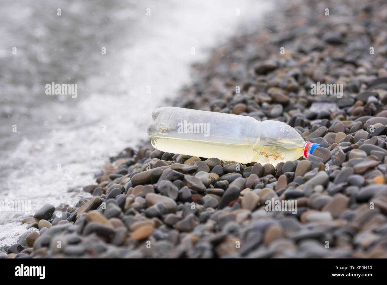 Plastic bottle lying on the pebbly seashore Stock Photo