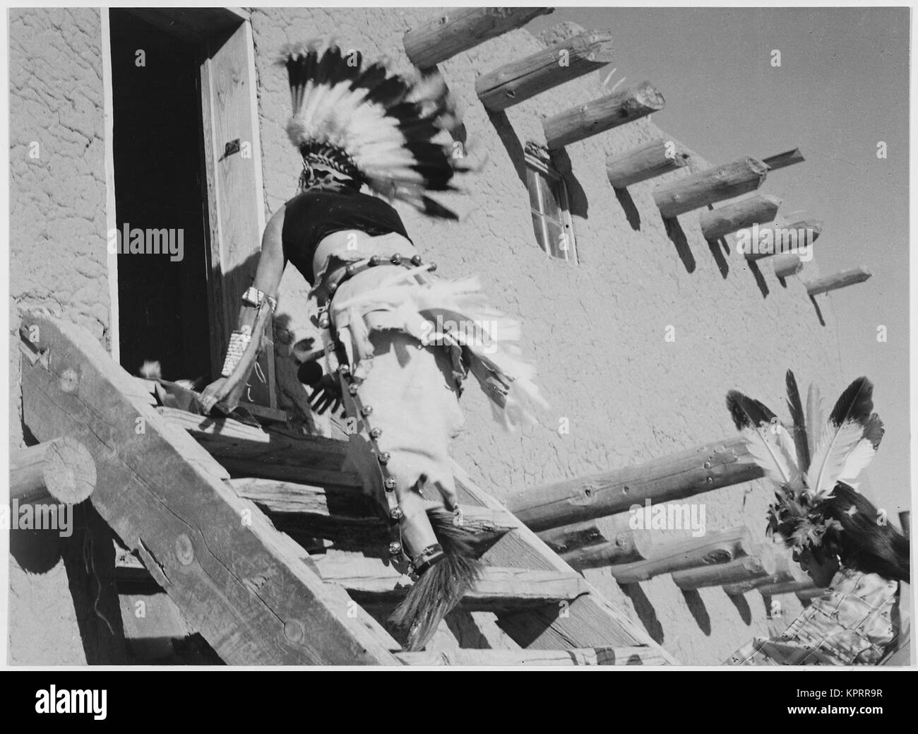 Dance San Ildefonso Pueblo New Mexico 1942 two Indians in headdress ascending stairs to house. 1942 Stock Photo