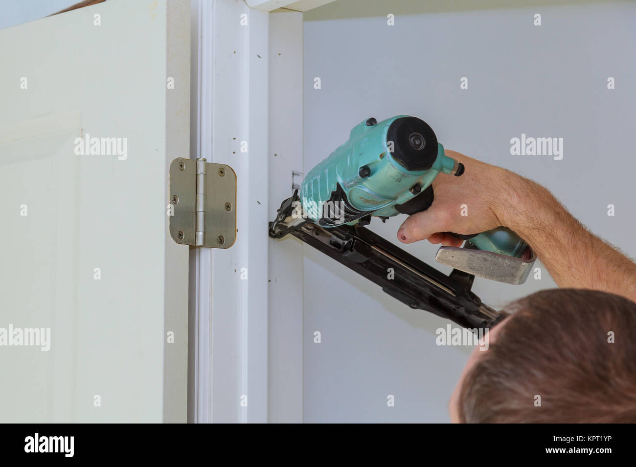 Carpenter brad using nail gun Installing new interior door, closeup