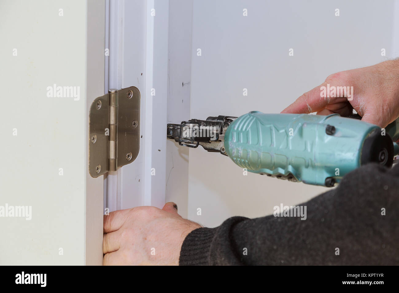 Worker using brad nail gun installs doors Carpenter using a nail gun