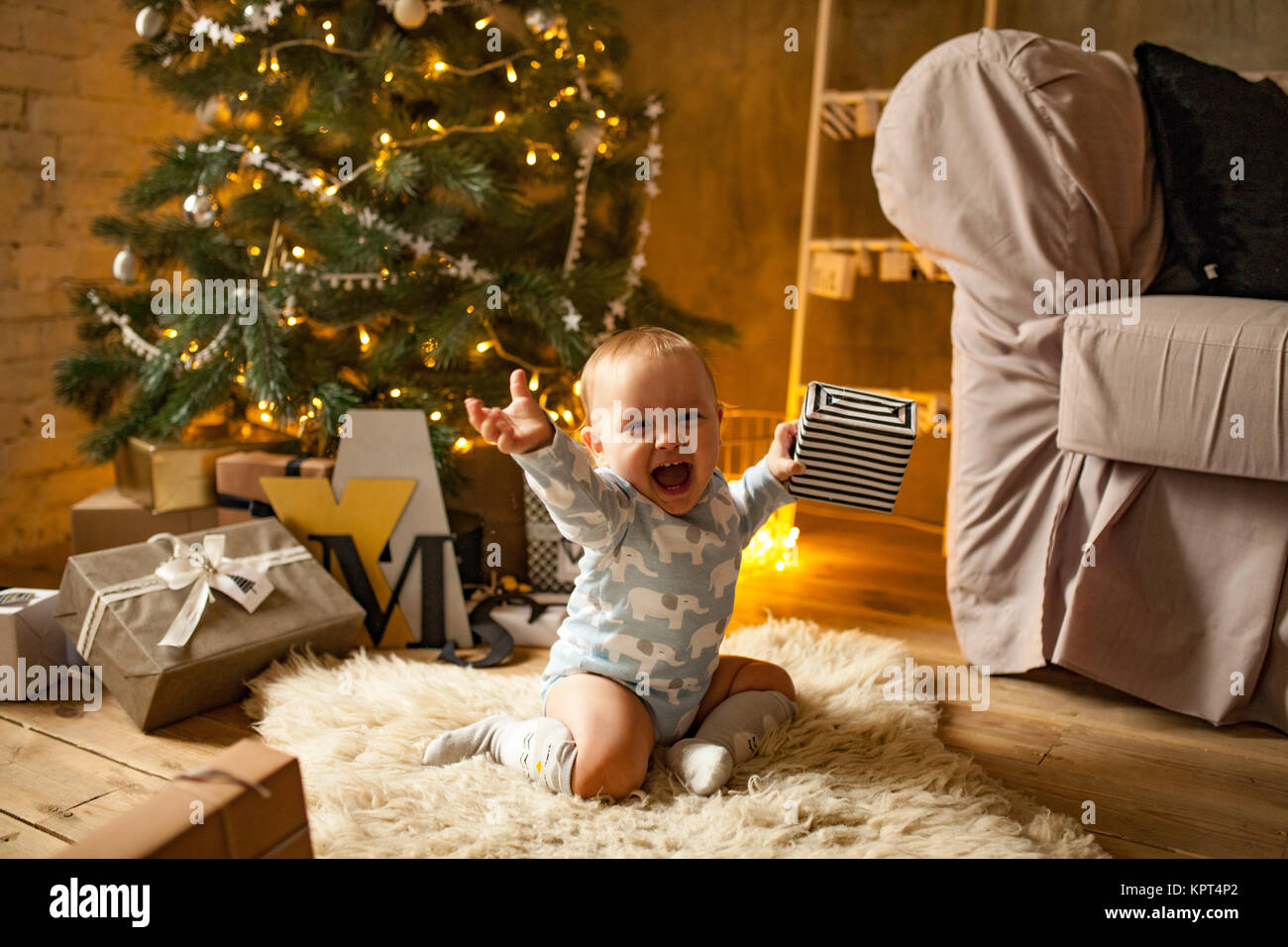 Little baby boy is happy with Christmas gift. He sits, laughs