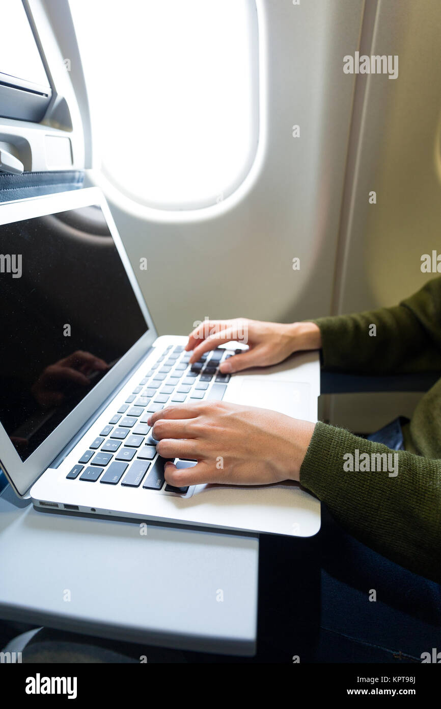 Woman using notebook computer inside airplane Stock Photo - Alamy