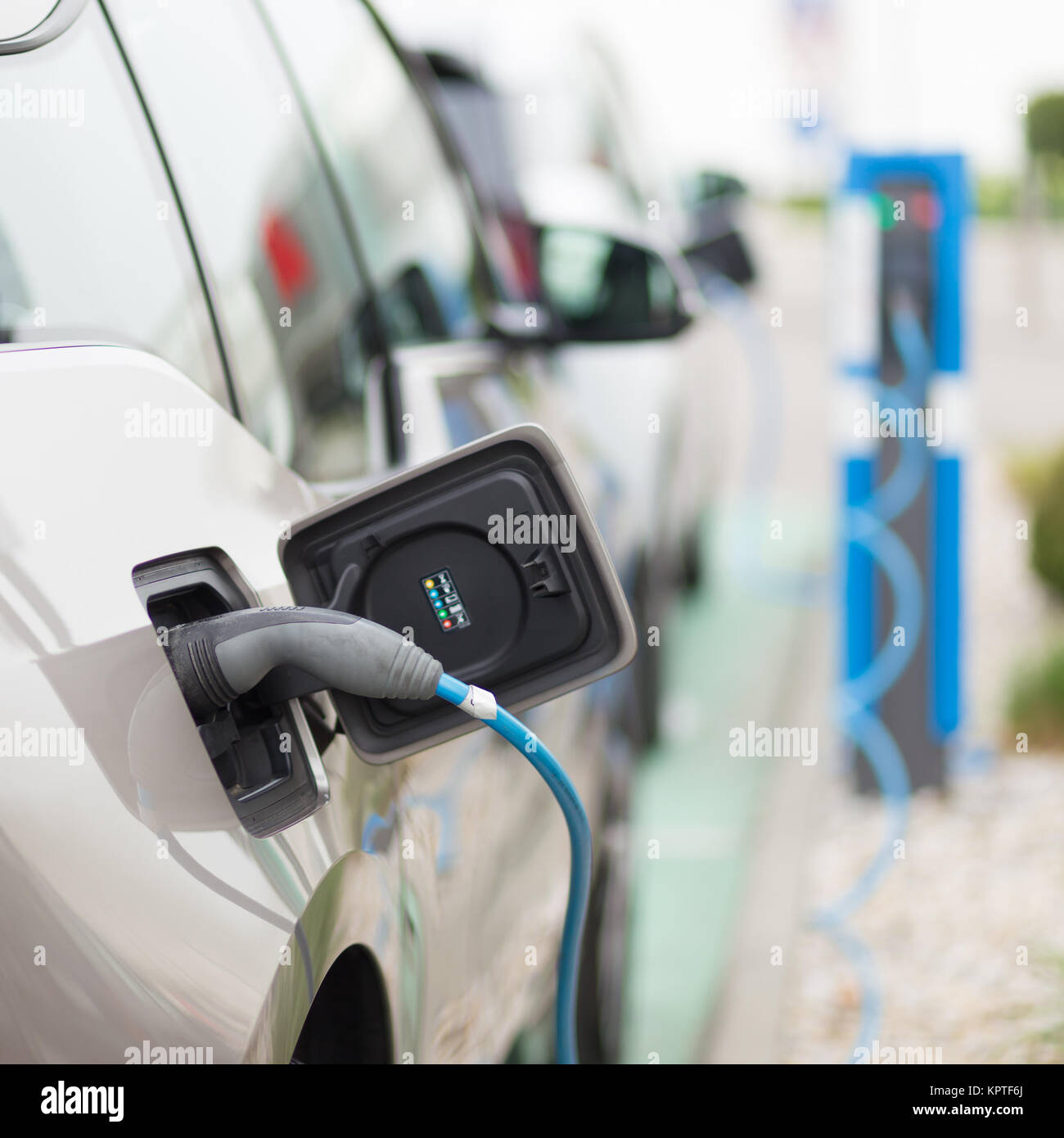 Power supply for electric car charging.  Electric car charging station. Close up of the power supply plugged into an electric car being charged. Stock Photo