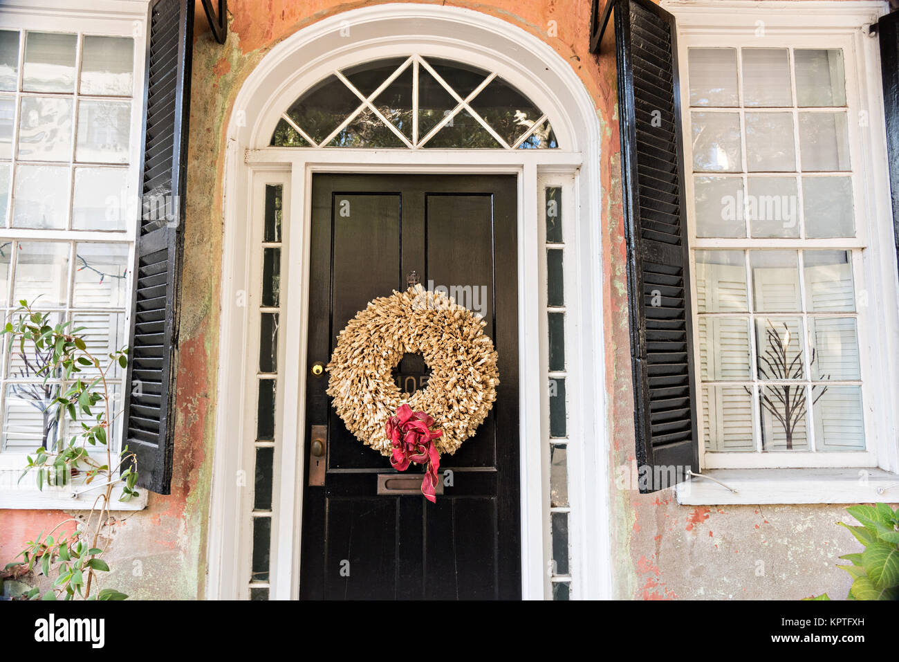 A wooden door of a historic home decorated with a Christmas wreath on Meeting Street in Charleston, SC. Stock Photo