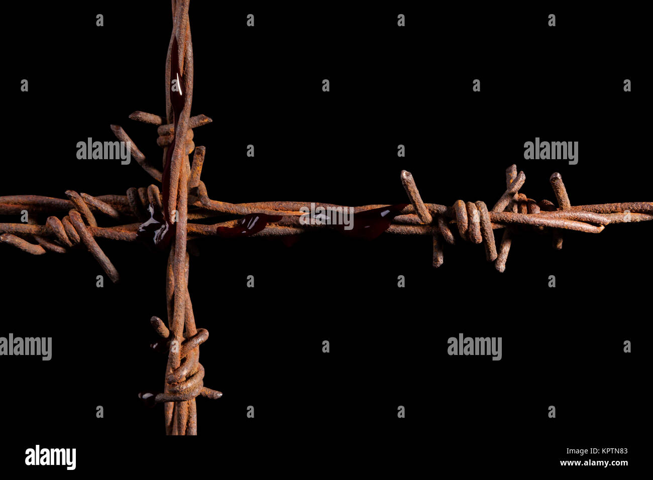 Rusty barb wire cross isolated on black background. Religious wars. Stock Photo