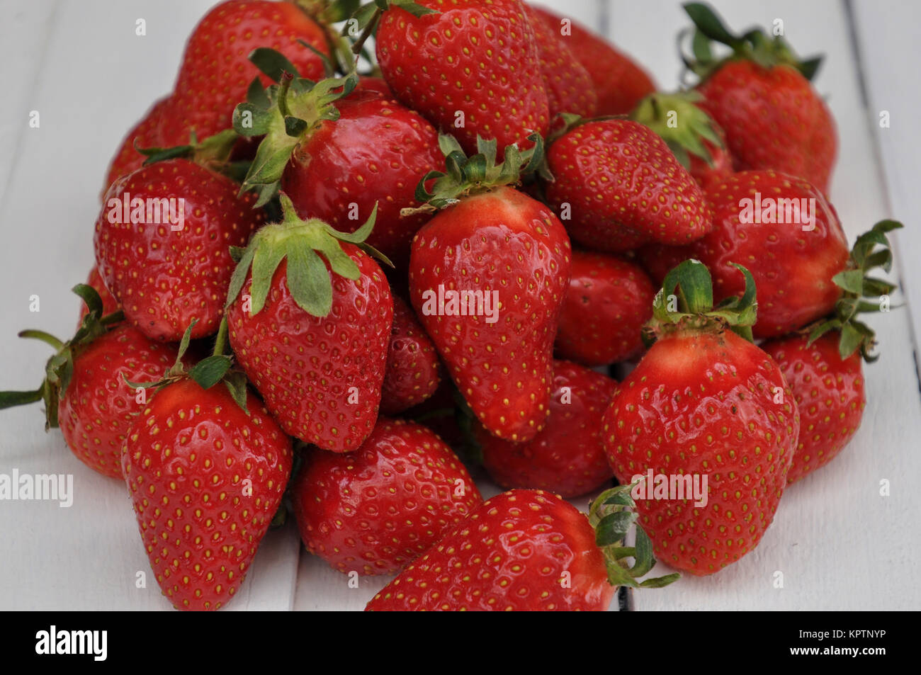 Lots of ripe red strawberries on a wooden white table Stock Photo - Alamy