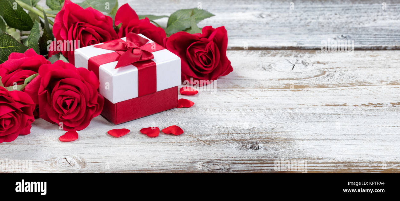 Gift box with red roses and hearts on rustic wood in close up view Stock Photo