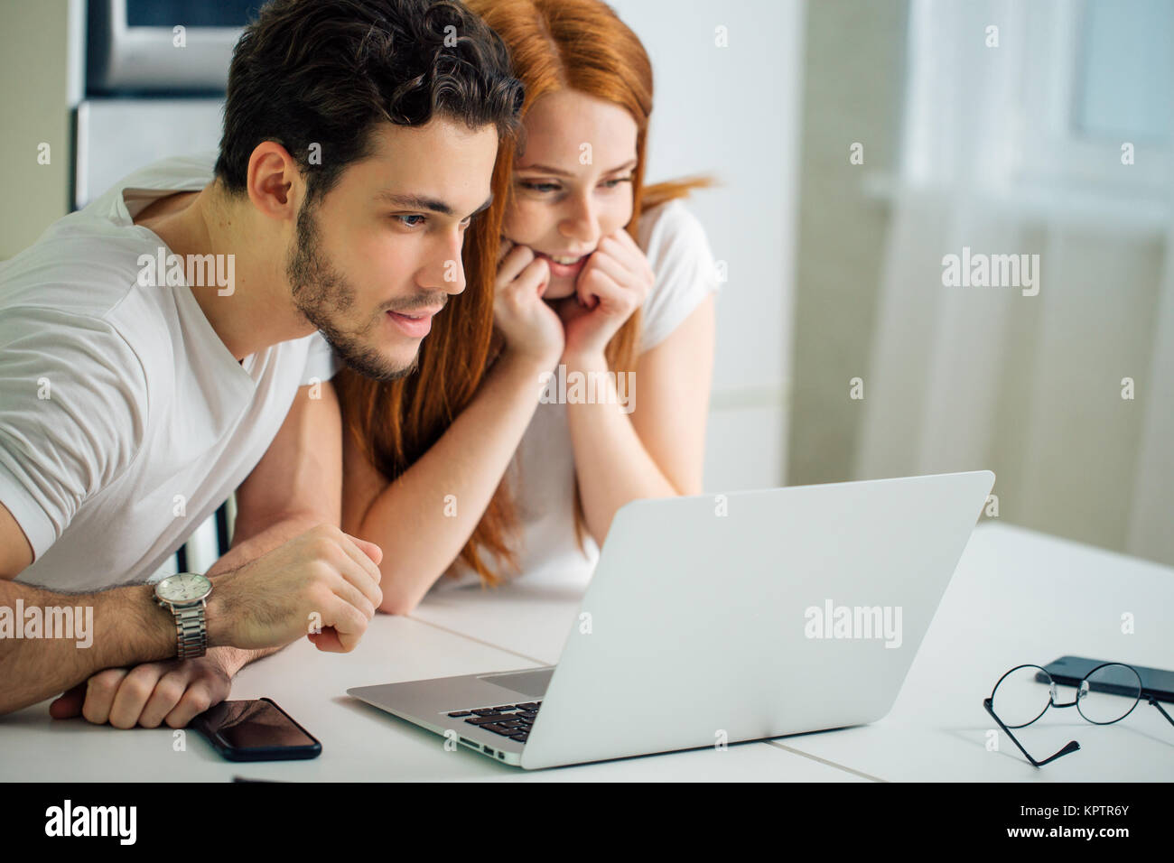 couple browsing internet together sitting at table and smiling and read ...
