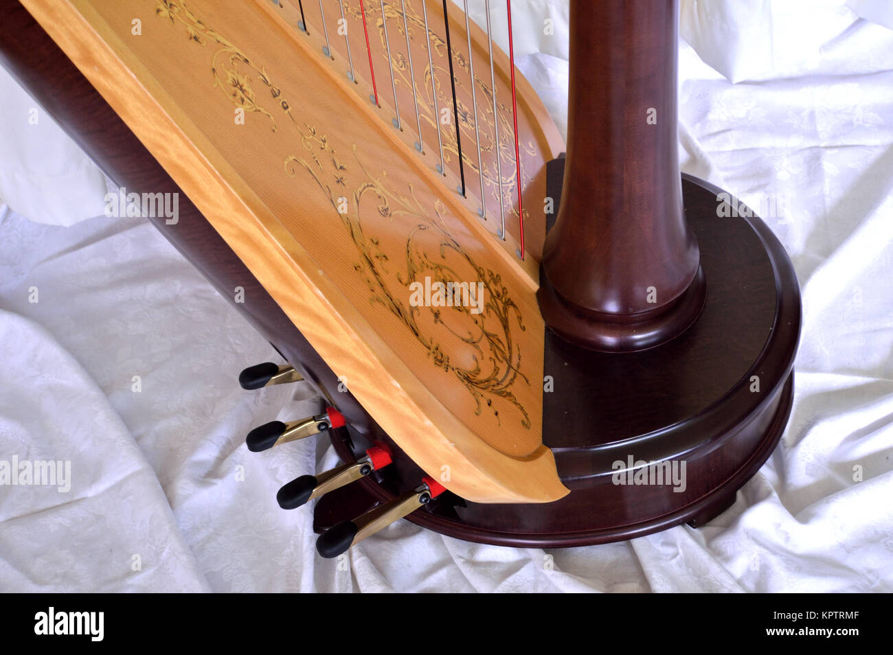 Closeup of the base of a dark wood, concert grand, pedal harp. Pedals