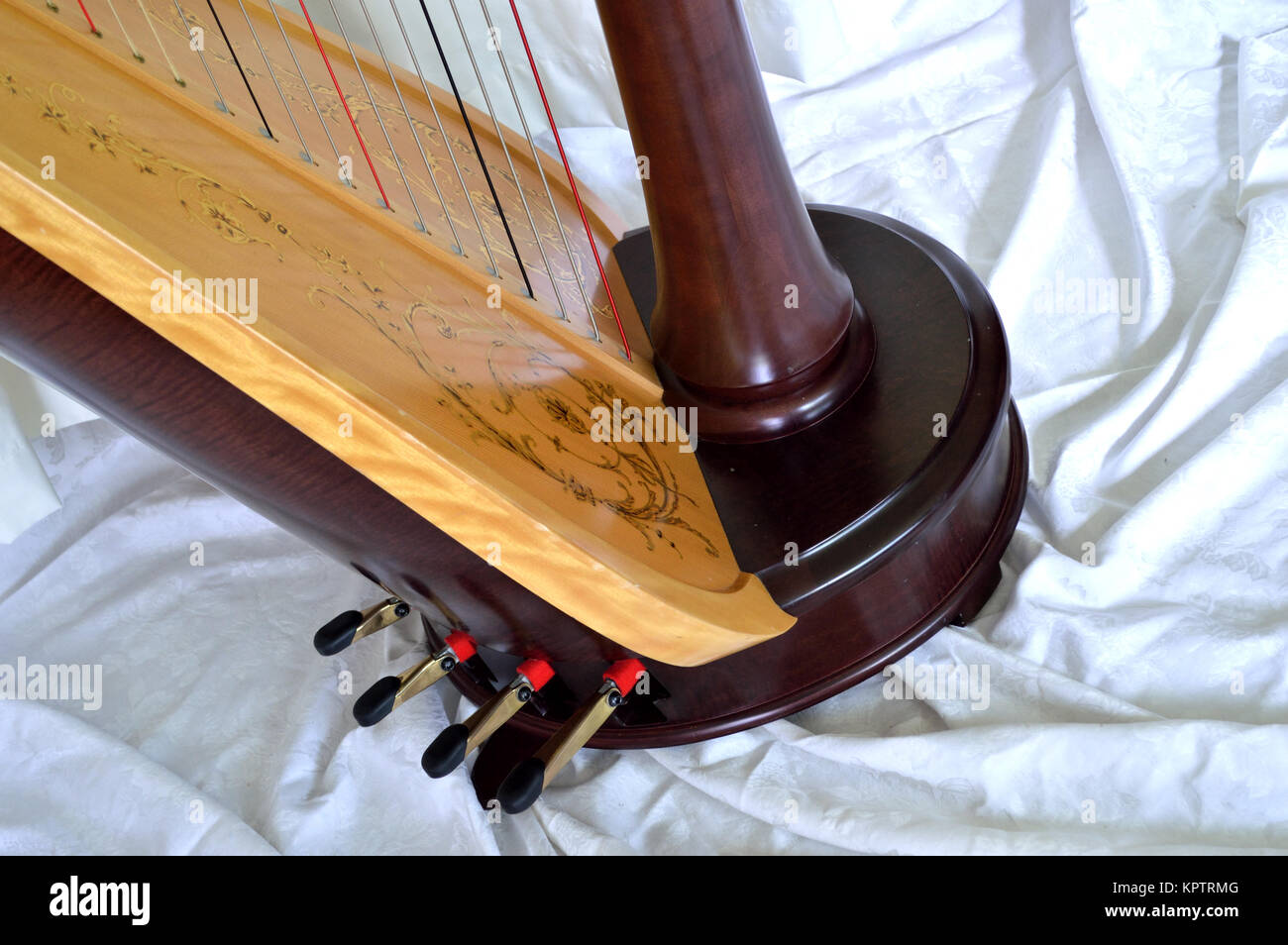 Closeup of the base of a dark wood, concert grand, pedal harp. Pedals